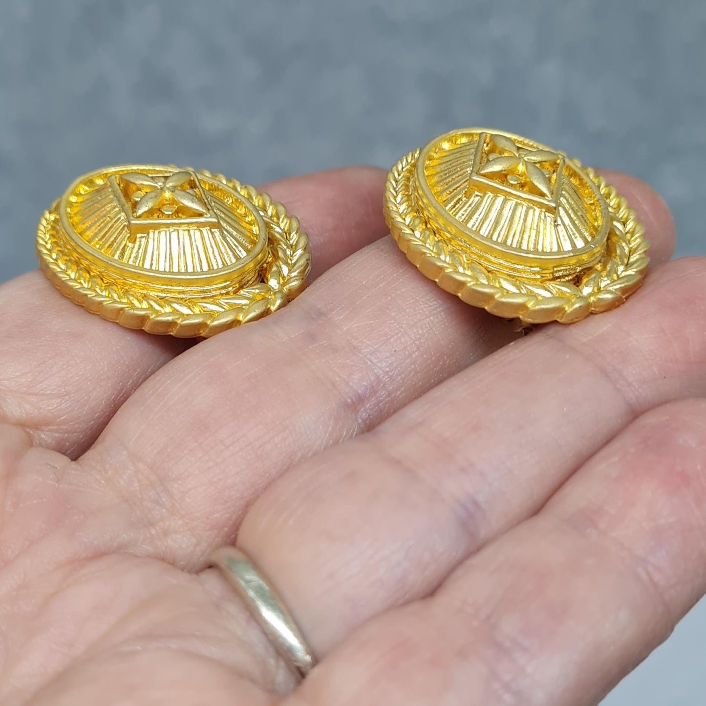 Vintage heraldic style clip-on earrings Matte gold tone textured metal oval clip earrings