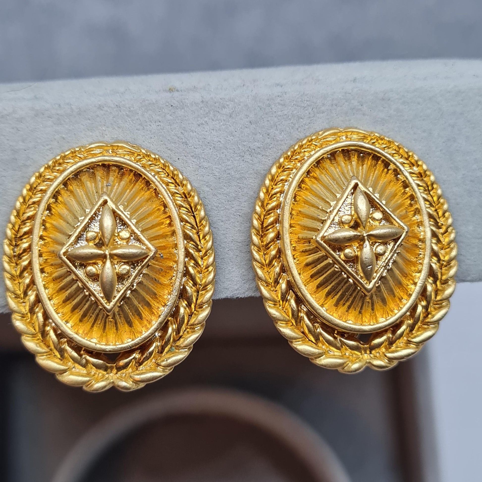 Vintage heraldic style clip-on earrings. Matte gold tone textured metal oval clip earrings.