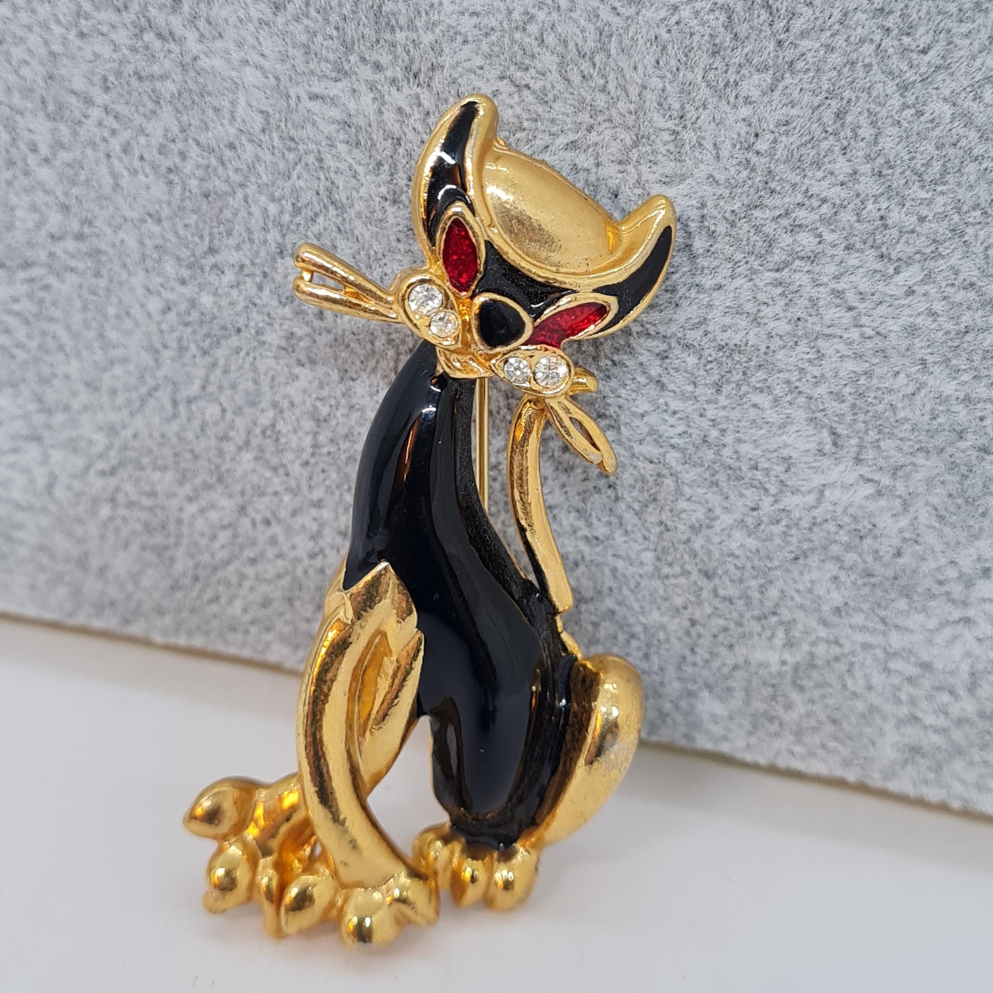 Vintage enamel cat brooch. Gold-tone metal with black and red enamel and clear rhinestone brooch pin.