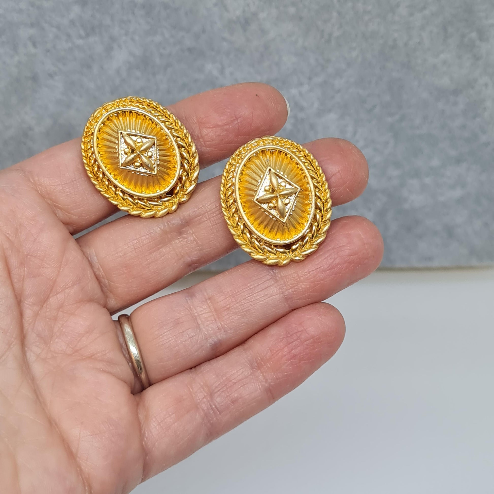 Vintage heraldic style clip-on earrings Matte gold tone textured metal oval clip earrings