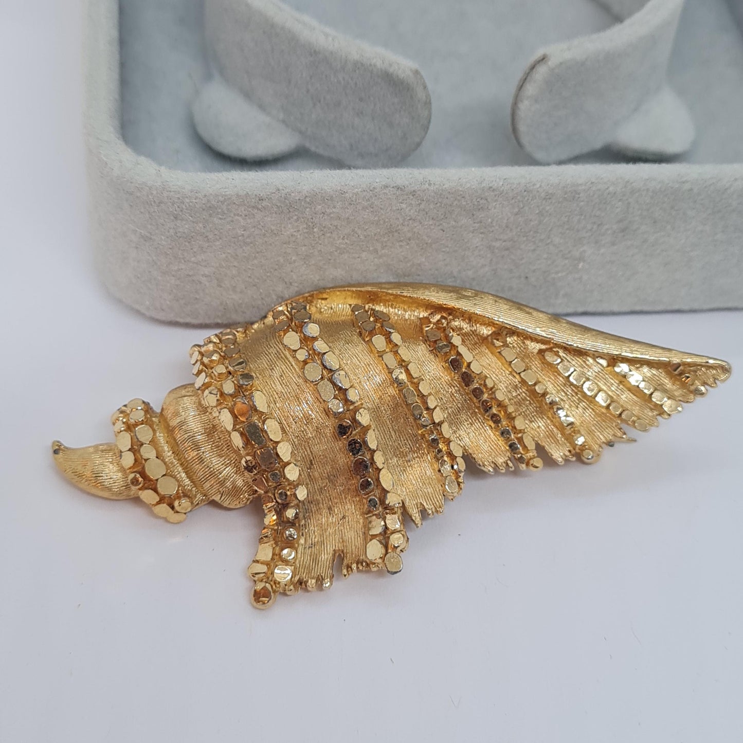 Vintage BSK seashell brooch with textured gold-tone metal pin.