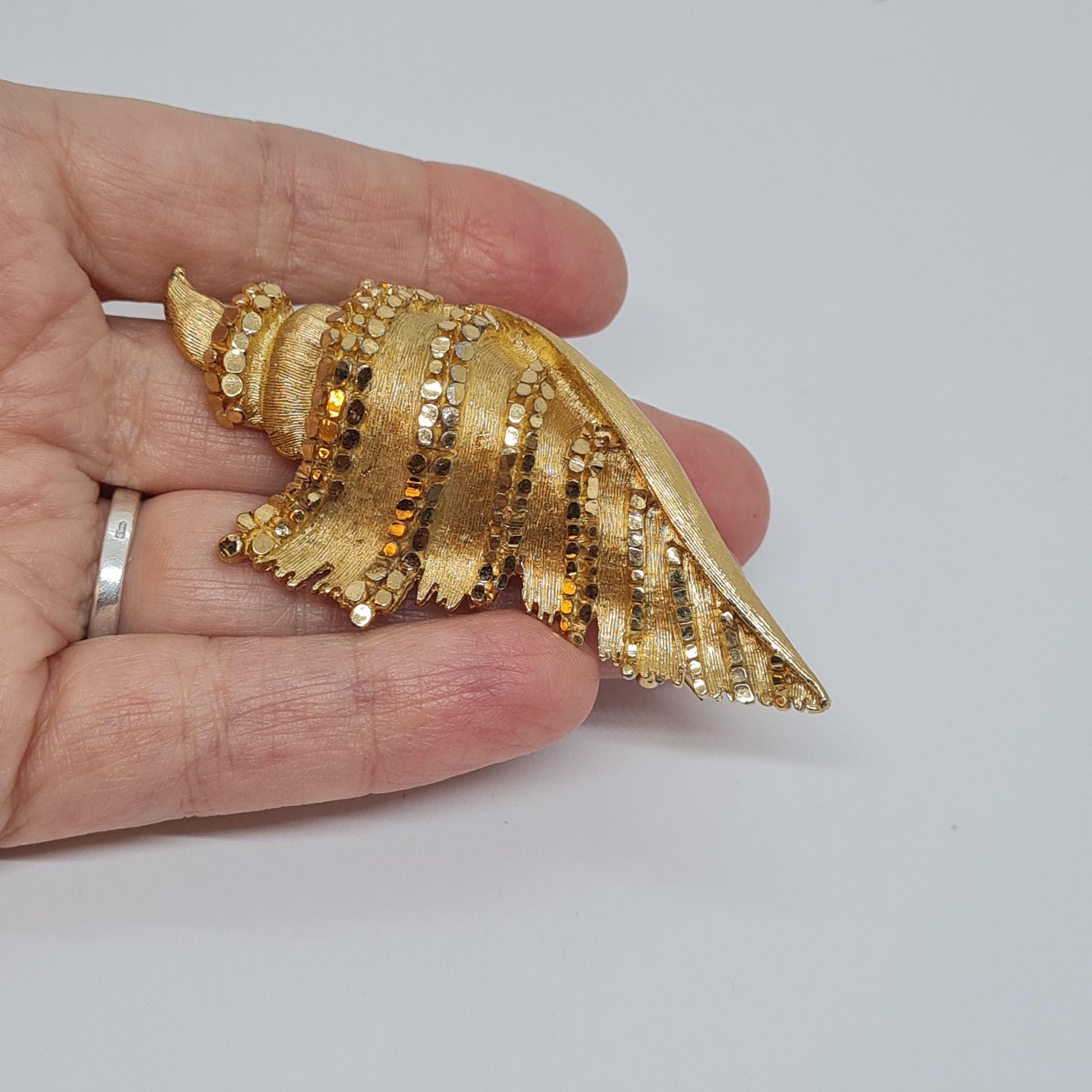 Vintage BSK seashell brooch with textured gold-tone metal pin.