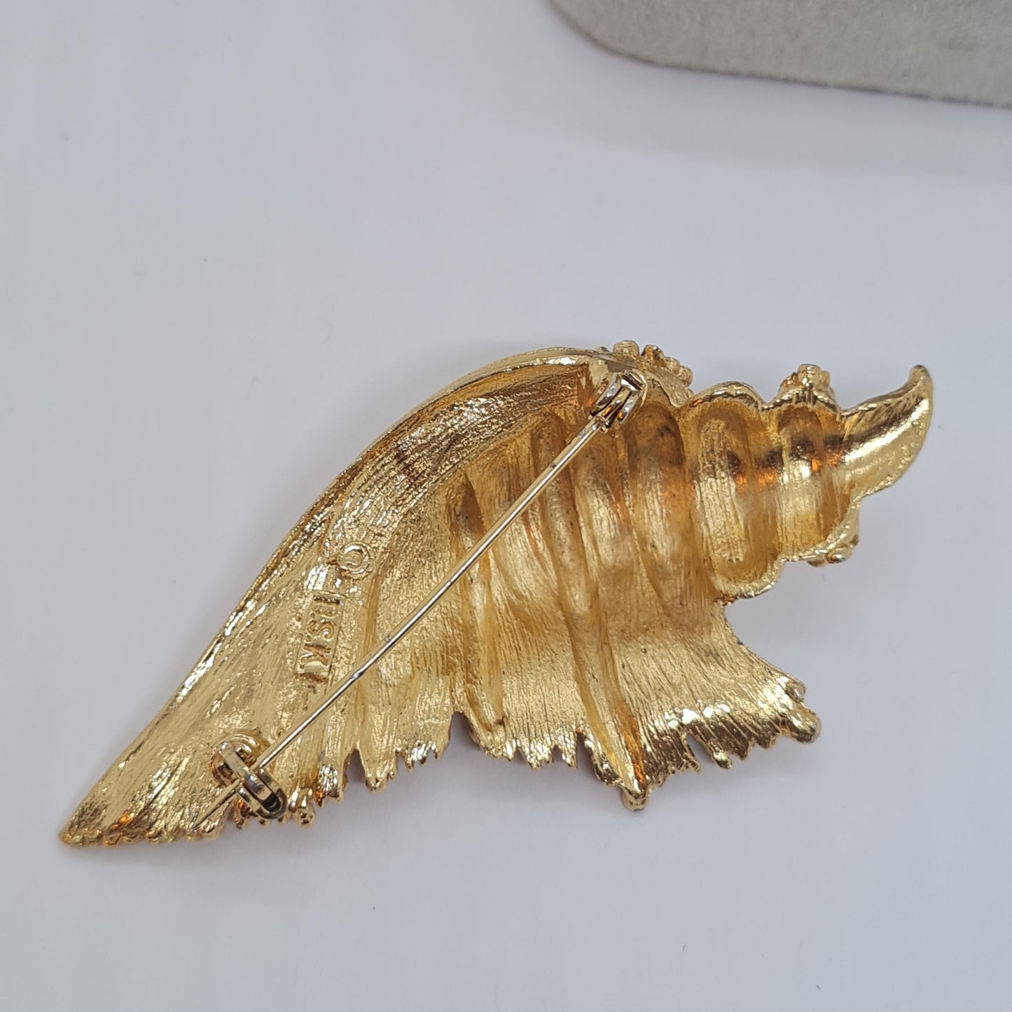 Vintage BSK seashell brooch with textured gold-tone metal pin.