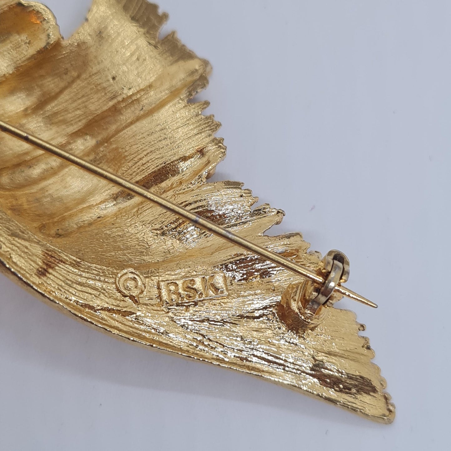 Vintage BSK seashell brooch with textured gold-tone metal pin.