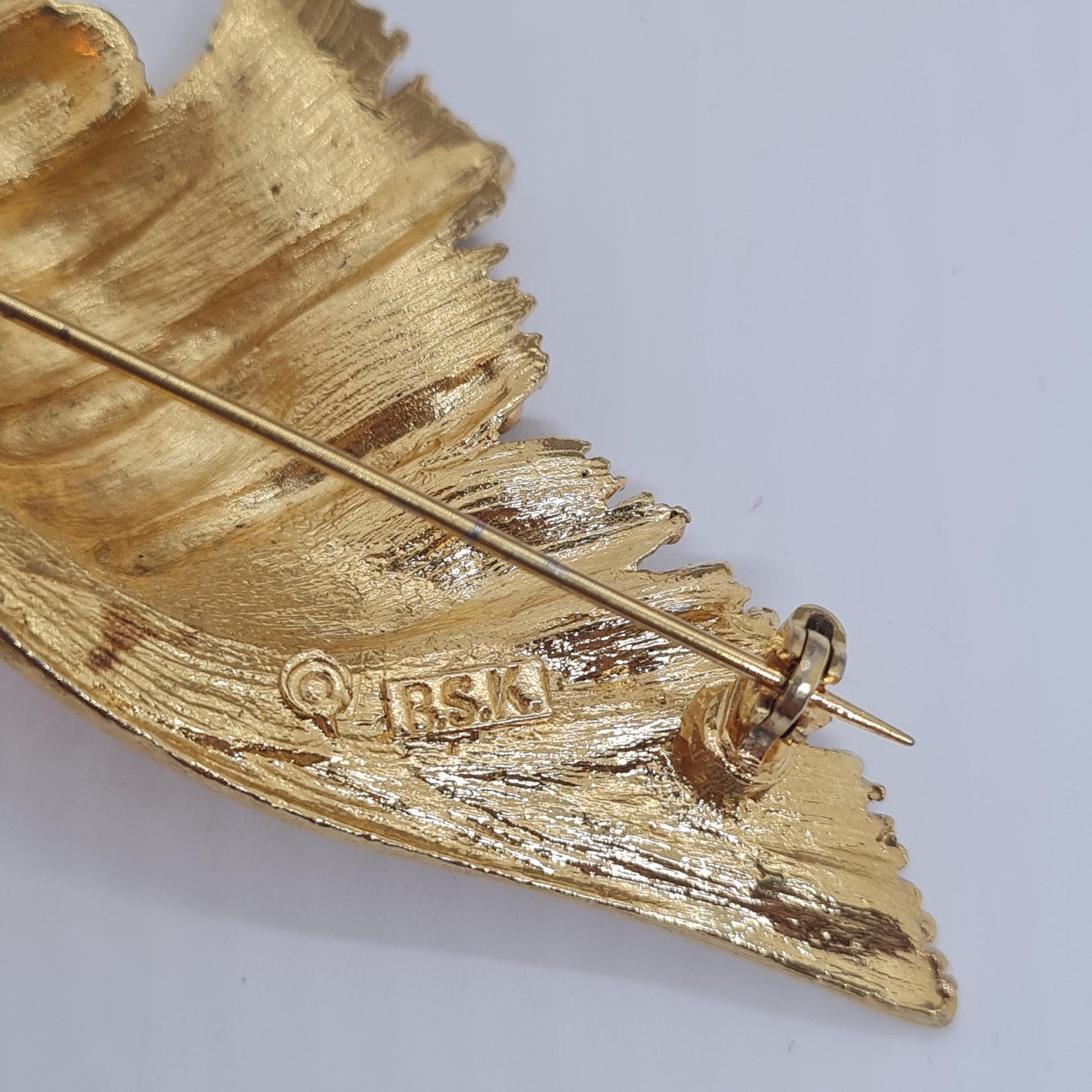 Vintage BSK seashell brooch with textured gold-tone metal pin.