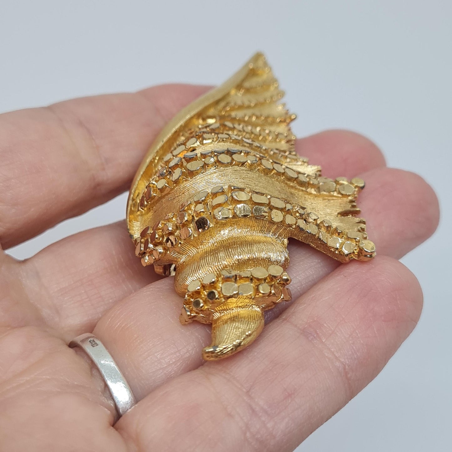 Vintage BSK seashell brooch with textured gold-tone metal pin.