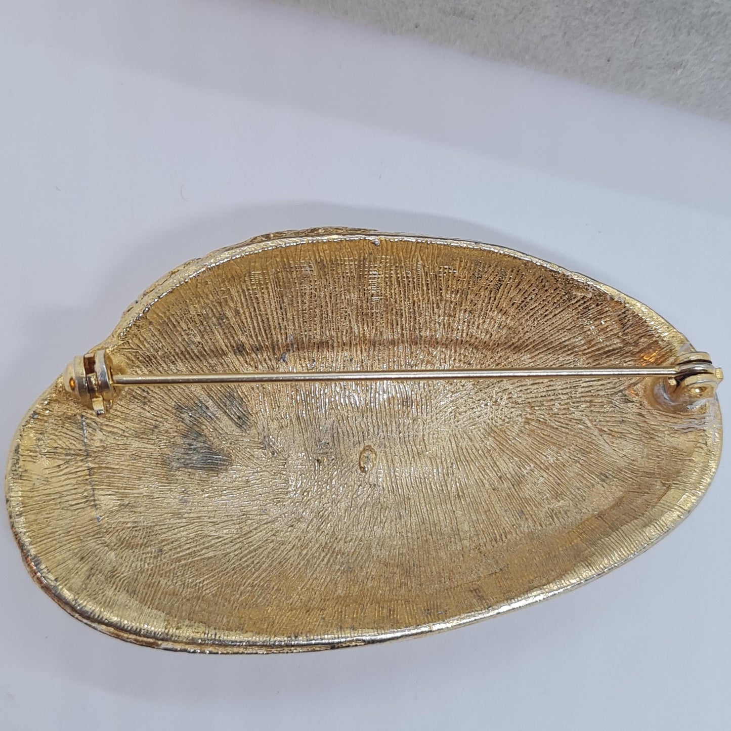 Vintage seashell brooch with textured gold-tone metal pin.