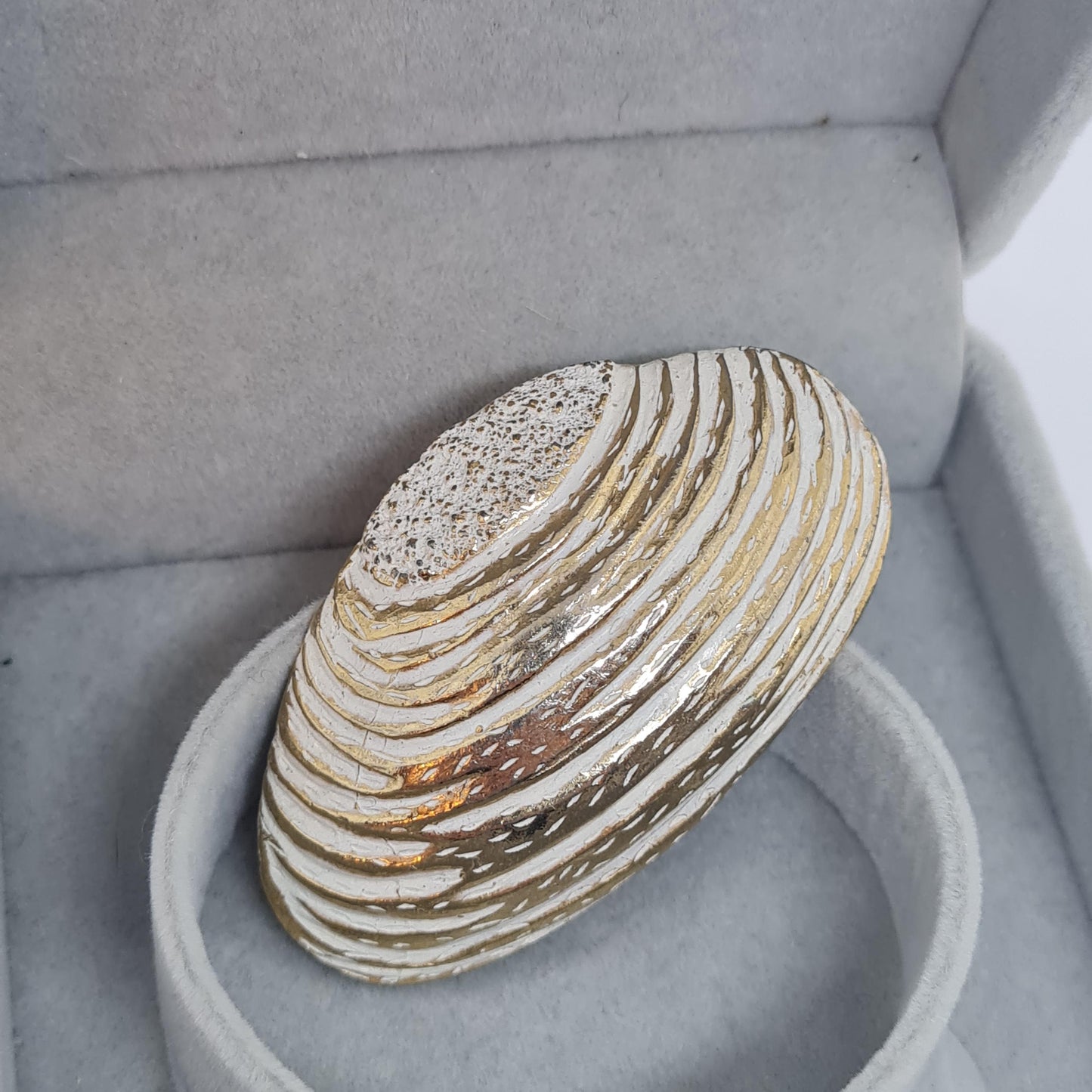 Vintage seashell brooch with textured gold-tone metal pin.