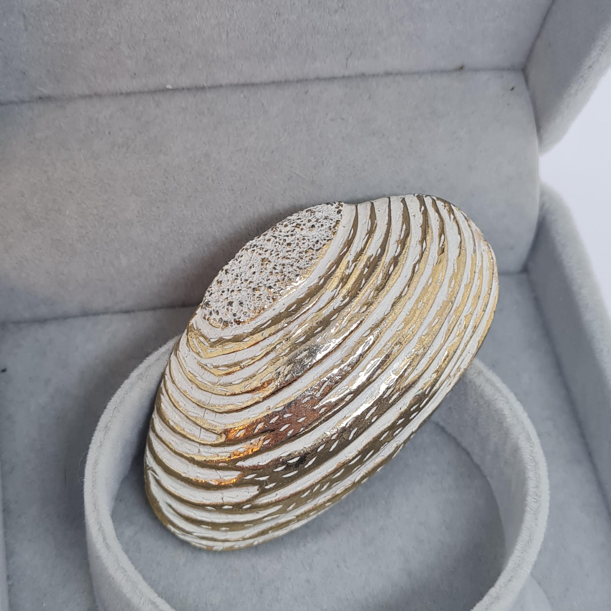 Vintage seashell brooch with textured gold-tone metal pin.