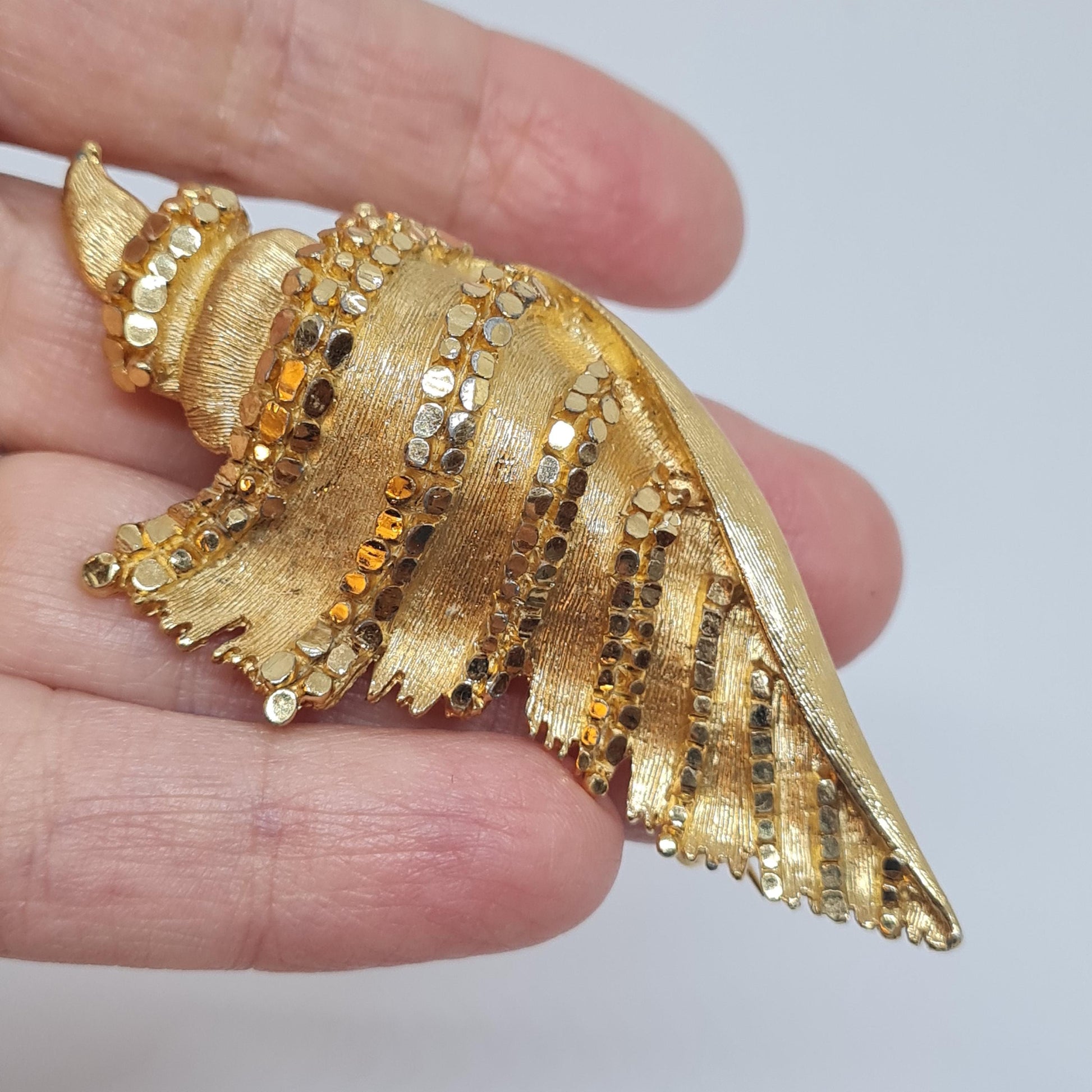Vintage BSK seashell brooch with textured gold-tone metal pin.