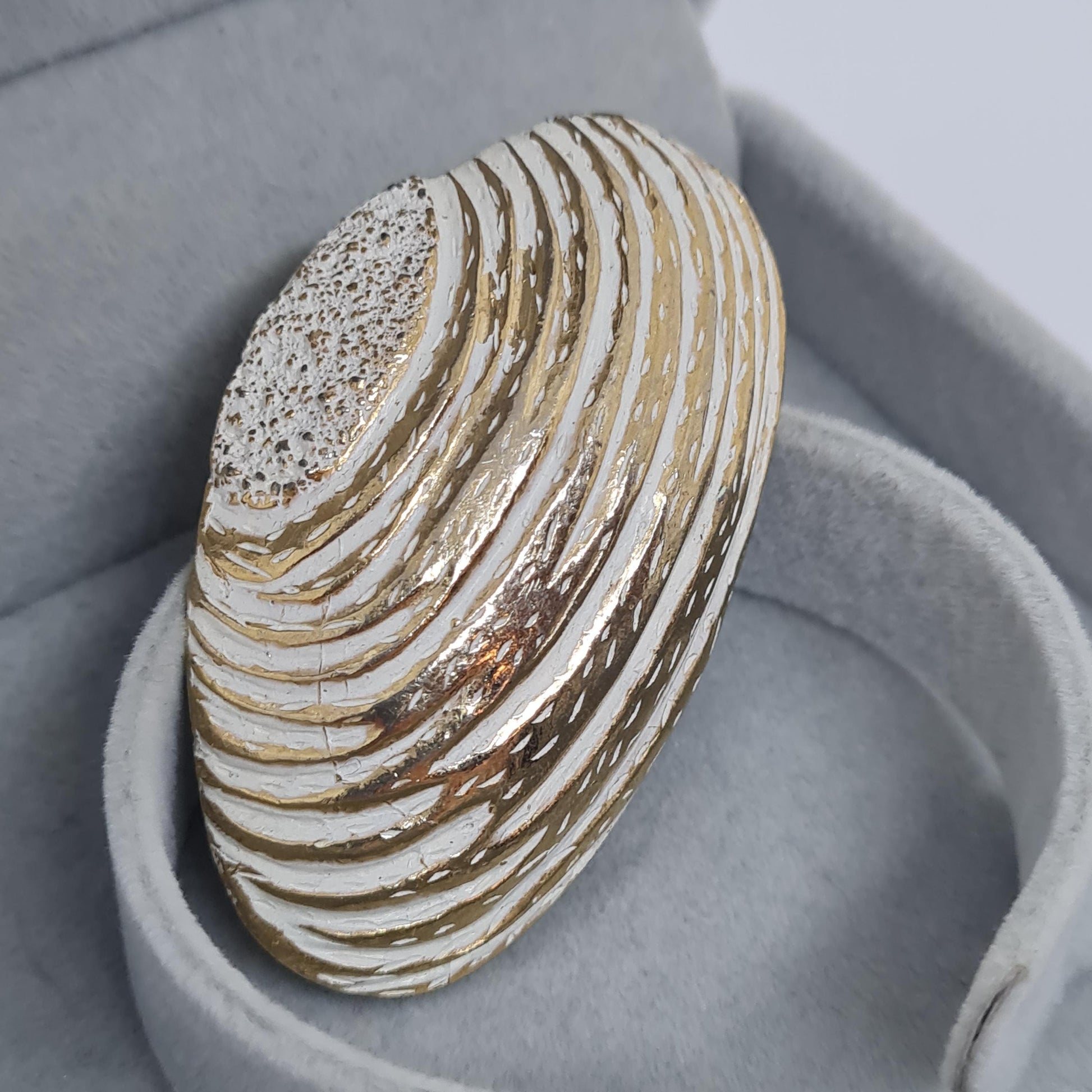 Vintage seashell brooch with textured gold-tone metal pin.